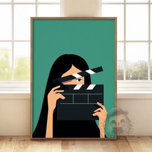 Puede incluir: Una impresión artística enmarcada que presenta a una mujer sosteniendo una claqueta de cine. La obra de arte tiene un fondo verde azulado y un estilo minimalista. La mujer tiene el pelo largo y negro y sostiene la claqueta frente a su rostro. El marco es de color madera natural.