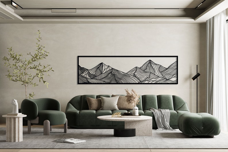 Puede incluir: Un dise&ntilde;o de interior de sala de estar con un sof&aacute; seccional de terciopelo verde, un sill&oacute;n de terciopelo verde, una mesa de caf&eacute; y una impresi&oacute;n de arte de l&iacute;nea en blanco y negro de monta&ntilde;as en la pared.