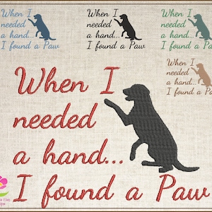 以下が含まれることがあります： リネン風の背景に刺繍されたアートワーク。「When I needed a hand... I found a Paw」のテキストが赤い筆記体で、黒い犬のシルエットが描かれています。青、緑、茶色で書かれた小さなテキストのバリエーションもあります。