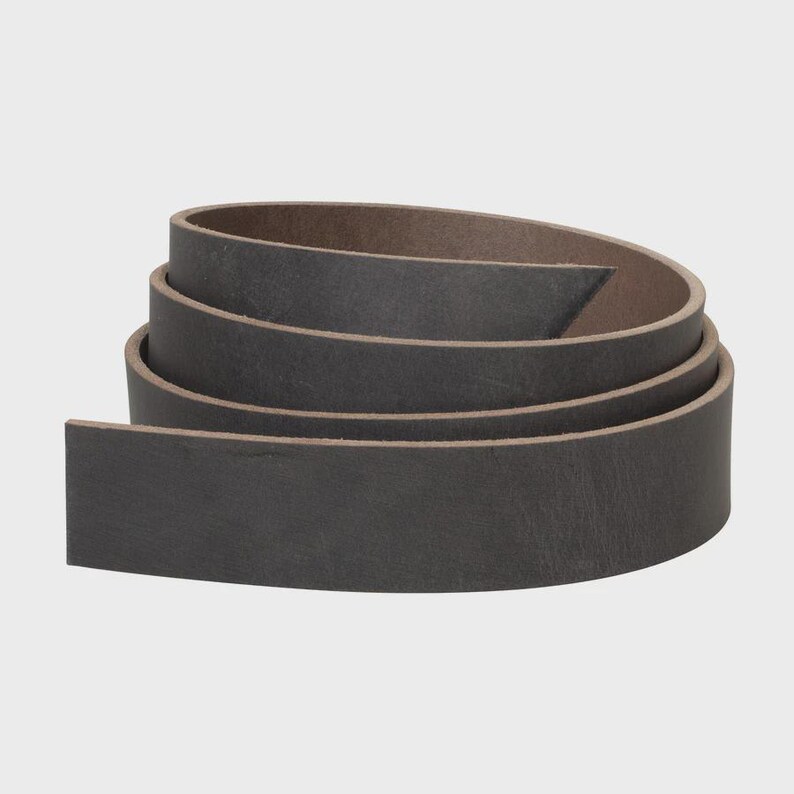 May include: A coiled strip of dark charcoal gray leather with a smooth, matte finish. The leather strap is wound into a circular shape, displaying a consistent dark gray color on the exterior and a slightly lighter brown tone on the interior.