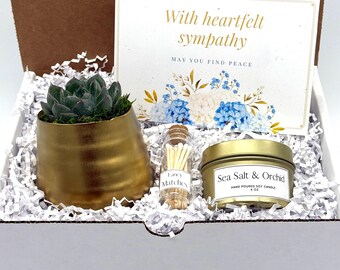 May include: A sympathy gift box containing a succulent in a gold pot, a candle, and a small bottle of matches. The candle is labeled "Sea Salt & Orchid" and the matches are labeled "Fancy Matches". A card with the text "With heartfelt sympathy" is also included.