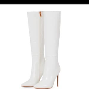 Könnte beinhalten: Ein Paar weiße, kniehohe Stiefel mit spitzer Zehenpartie und Stiletto-Absatz.