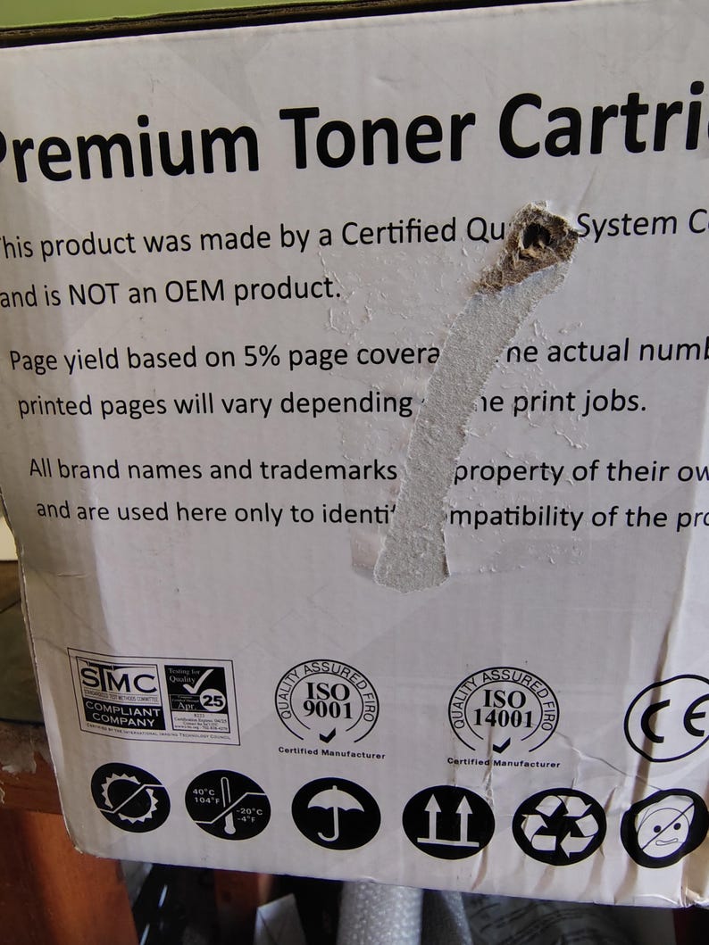 May include: White cardboard box with text that reads "Premium Toner Cartridge." The box includes various certification logos, including ISO 9001 and ISO 14001. The text also mentions that the product is not an OEM product.