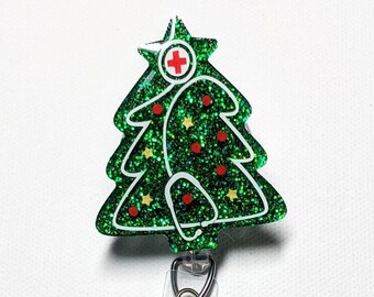 May include: A green glitter Christmas tree badge reel with a white outline, red accents, and a medical cross. The badge reel has a clear plastic strap and a metal clip.