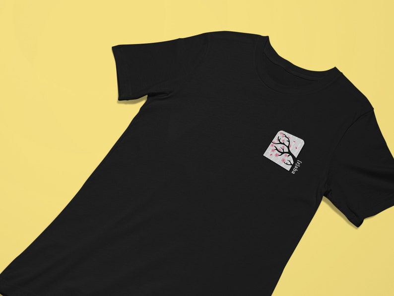 May include: Black t-shirt with a white square pocket featuring a pink cherry blossom tree and the word "Japan" written vertically.