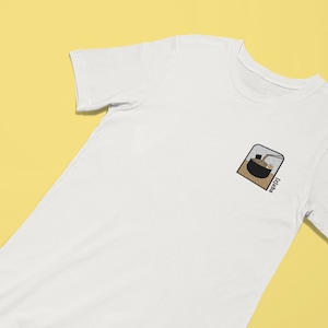 Puede incluir: Camiseta blanca con una peque&ntilde;a imagen bordada de un cuenco de fideos ramen con la palabra "Ramen" escrita debajo.