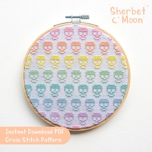 Puede incluir: Un patrón de punto de cruz de colores arcoíris con un patrón repetido de calaveras. El patrón se muestra en un aro de bordado de madera. El texto "Sherbet C Moon" y "Descarga instantánea PDF Patrón de punto de cruz" es visible debajo del aro.