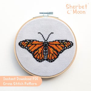 May include: A cross stitch pattern featuring a monarch butterfly with orange, black, and white wings. The pattern is in a wooden embroidery hoop and is ready to be stitched.
