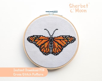 May include: A cross stitch pattern featuring a monarch butterfly with orange, black and white wings. The pattern is in a wooden embroidery hoop and is ready to be stitched.
