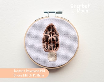 May include: A cross stitch pattern of a brown and beige morel mushroom on a light purple background. The pattern is framed in a wooden hoop. The text "Sherbet & Moon" and "Instant Download PDF Cross Stitch Pattern" is visible.