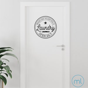 Könnte beinhalten: Eine weiße Tür mit einem schwarz-weißen Wäschezimmer-Schild, auf dem "Wash, Dry, Fluff, Fold, Laundry, Open 24/7" steht.