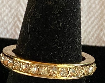 May include: A gold band ring with a row of clear sparkling stones.