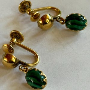 May include: A pair of gold tone clip-on earrings with green malachite stones.