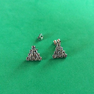May include: A pair of silver triangle-shaped earrings with clear rhinestones.