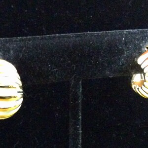 Pode incluir: Um par de brincos de argola de ouro com um design canelado. Os brincos estão em um expositor preto.