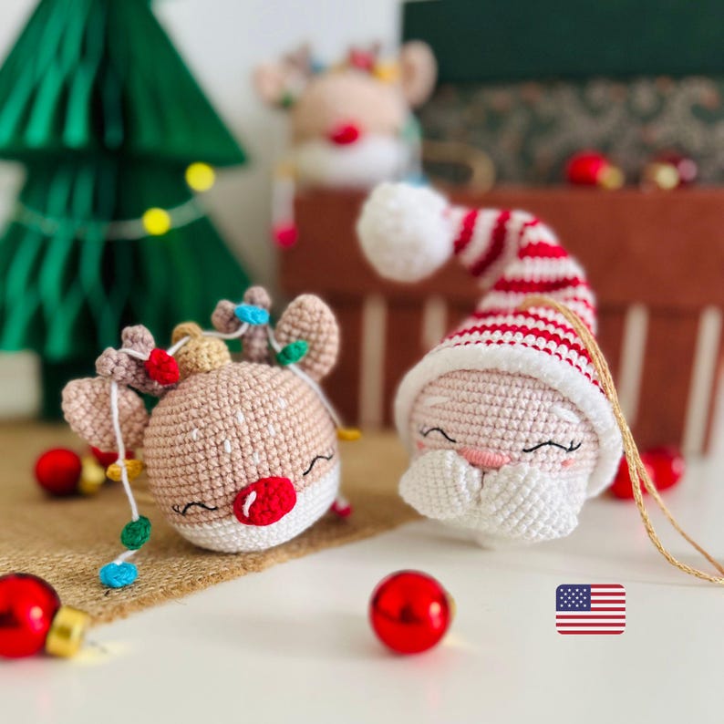 May include: Crocheted Christmas ornaments featuring a reindeer with string lights and a Santa Claus with a red and white striped hat. The ornaments are beige, red, white, and green. Red Christmas ball ornaments are scattered around the scene.