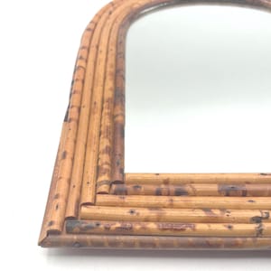 May include: An arched wall mirror featuring a frame constructed from multiple layers of light brown bamboo stalks with dark brown mottled markings. The frame has a layered, tiered design that follows the curved top and straight bottom edges.