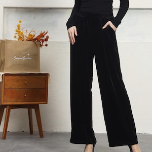 May include: Black velvet wide-leg pants with a black top and black heels. The pants have a wide waistband and a relaxed fit.