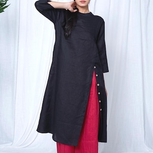 May include: A black tunic-style top with three-quarter sleeves and a side slit, buttoned with white buttons. The top is paired with bright red pants. The outfit is simple and elegant, suitable for casual or semi-formal wear.