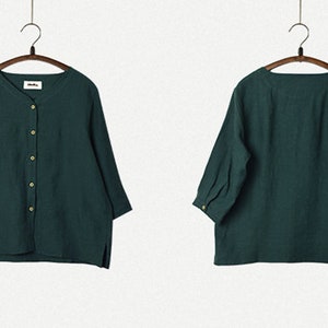 May include: A dark green, button-up shirt with three-quarter sleeves. The shirt is hanging on a wooden hanger.