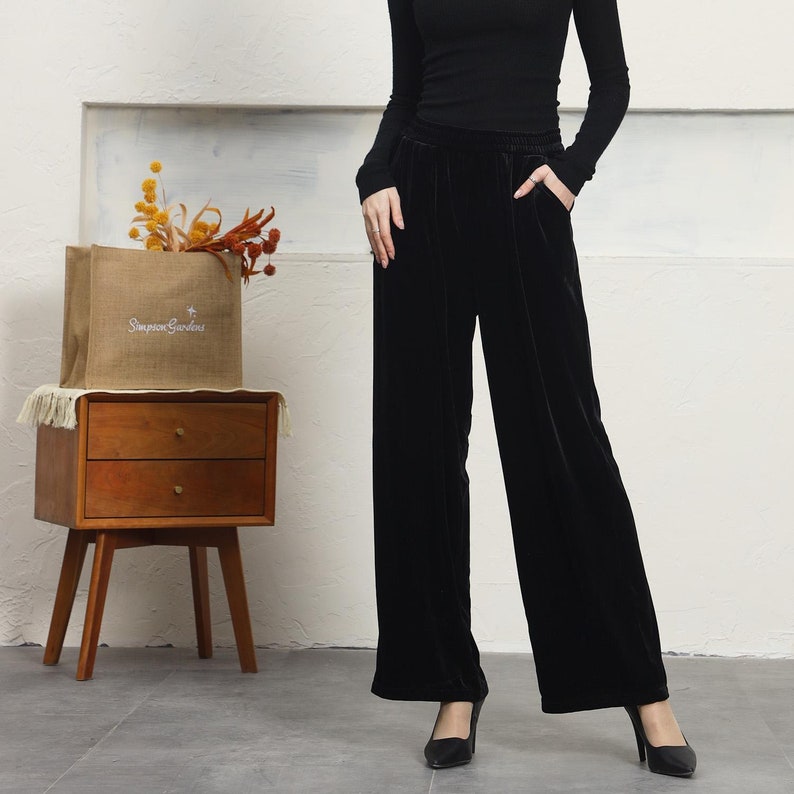 May include: Black velvet wide-leg pants with a black top and black heels. The pants have a wide waistband and a relaxed fit.