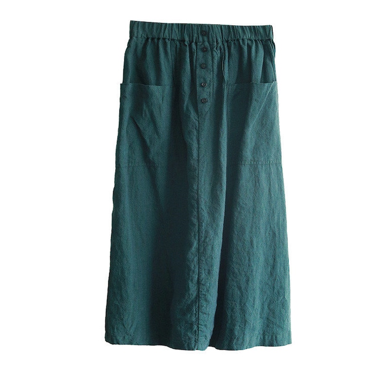 May include: A dark green linen skirt with a button fastening and two large pockets. The skirt has a relaxed fit and a midi length.