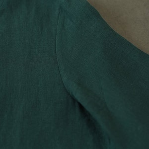 May include: Close-up of a dark green linen fabric with a smooth texture.