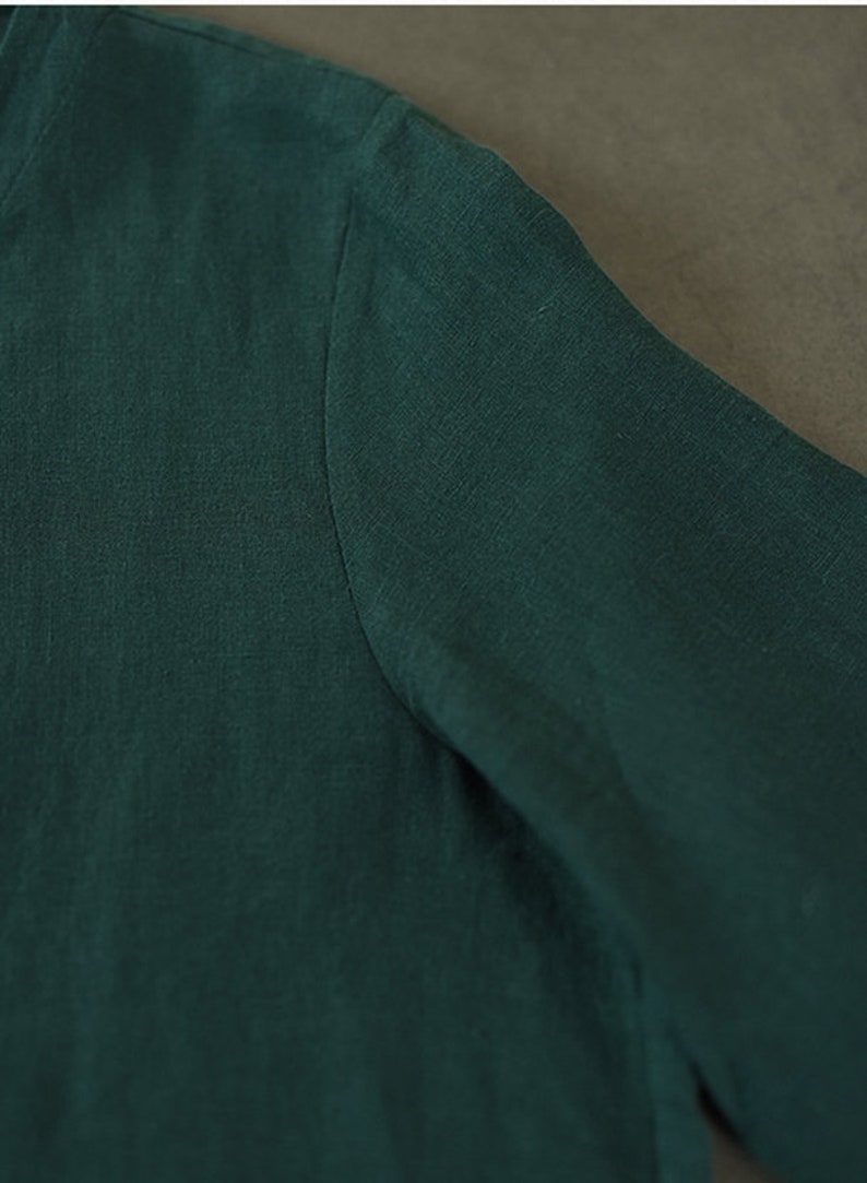 May include: Close-up of a dark green linen fabric with a smooth texture.