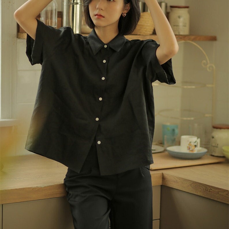 May include: A black collared shirt with short sleeves and a button-up front. The shirt is made of a lightweight fabric and has a relaxed fit.