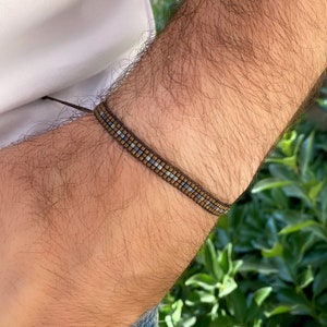 Könnte beinhalten: Ein braunes und blaues Perlenarmband mit einer schwarzen Schnur.
