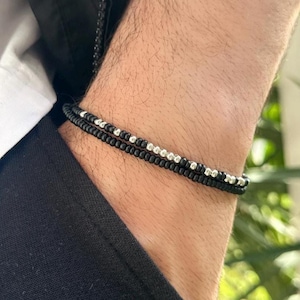 Può includere: Un braccialetto a doppio filo con perline nere e argentate.