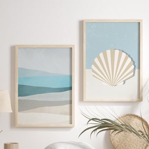 May include: Two framed prints with a beach theme. The print on the left shows a blue and white abstract design of a beach scene. The print on the right shows a beige seashell on a blue background. A wooden bench with a white pillow sits in front of the prints. A woven basket sits on the floor in front of the bench. A potted plant with green leaves sits on the floor to the right of the bench.