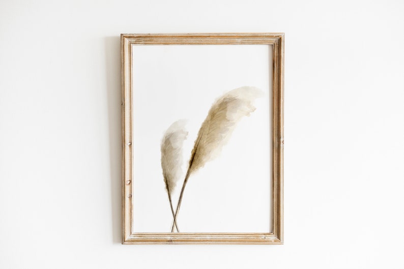 May include: A framed print of two dried pampas grass stems in shades of beige and brown against a white background.