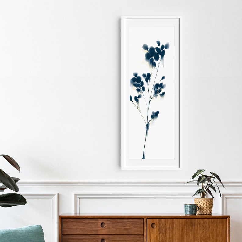 Peut inclure: Une peinture &agrave; l'aquarelle encadr&eacute;e d'une branche florale bleue et blanche. La peinture est dans un cadre blanc et est accroch&eacute;e &agrave; un mur blanc.