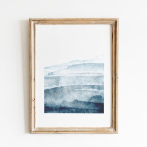 May include: A framed abstract watercolor painting with a blue and white color scheme. The painting features a series of horizontal brushstrokes that create a layered effect.