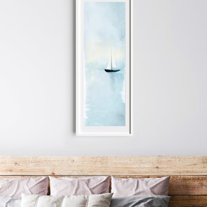 Peut inclure: Une peinture &agrave; l'aquarelle encadr&eacute;e d'un voilier sur une mer bleue calme. Le ciel est bleu clair avec des touches de nuages blancs. Le voilier est blanc avec une coque noire.