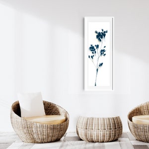 Peut inclure: Deux chaises en osier avec coussins et une table en osier devant un mur blanc avec une estampe encadr&eacute;e en noir et blanc d'une plante stylis&eacute;e.