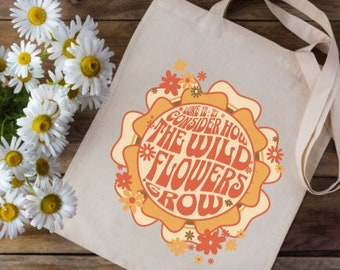 May include: A white canvas tote bag with a colorful floral design and the text "Consider how the wild flowers grow".