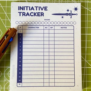 以下が含まれることがあります： 青い文字と剣のグラフィックが描かれた白いイニシアチブトラッカー。トラッカーには、キャラクター名、アーマー・クラス、ヒットポイント、メモの15行があります。