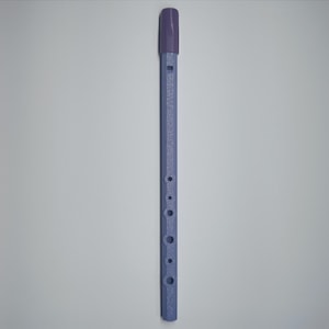 Puede incluir: Un silbato de hojalata morado y azul. El silbato tiene un cuerpo cilíndrico con varios agujeros y una boquilla. La boquilla es de un tono morado más oscuro que el cuerpo. El instrumento está diseñado para ser tocado soplando en la boquilla.