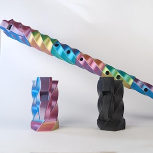Peut inclure: Trois sifflets décoratifs. L'un est un long design irisé aux couleurs de l'arc-en-ciel avec des trous. Deux petits sifflets sont également présents, l'un aux couleurs de l'arc-en-ciel irisé et l'autre noir. Tous ont un design torsadé.