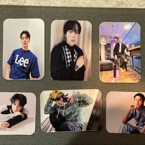May include: Six photo cards featuring different images of a young man. The cards are white with a rectangular shape. The images are in color and show the man in various poses and outfits. The man is wearing a blue shirt with the word "Lee" on it, a black jacket, a plaid shirt, a yellow baseball cap, a black and white striped shirt, and a gray turtleneck.