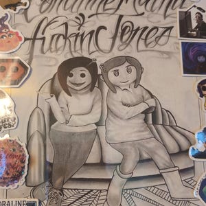 May include: Framed artwork featuring a pencil sketch of two characters from the movie "Coraline" seated on a couch. The artwork includes the text "Coraline Mutha Fucking Jones" in stylized lettering, along with various character stickers.