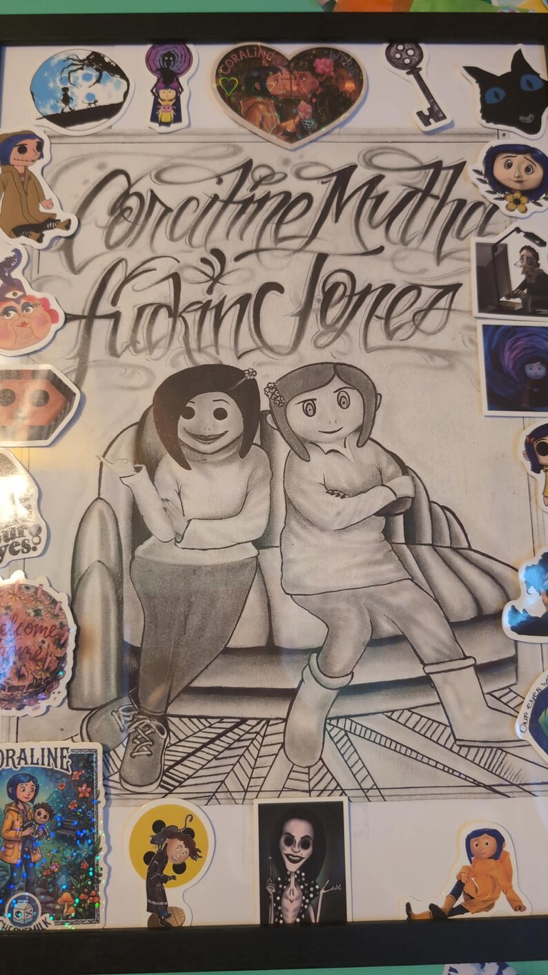 May include: Framed artwork featuring a pencil sketch of two characters from the movie "Coraline" seated on a couch. The artwork includes the text "Coraline Mutha Fucking Jones" in stylized lettering, along with various character stickers.