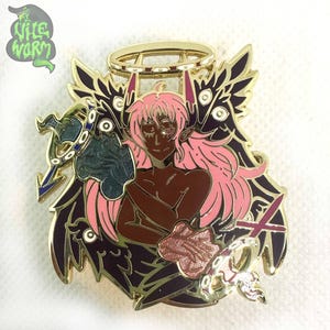 May include: Gold-tone enamel pin featuring a pink-haired figure with a halo, surrounded by black wings and holding a sword and a staff. The figure has brown skin and closed eyes.