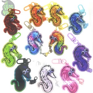 Puede incluir: Un conjunto de 10 llaveros coloridos con forma de gusano y ojos saltones. Cada llavero está hecho de acrílico y presenta un color y diseño diferente. Los llaveros están unidos a anillos y cadenas metálicas.