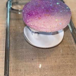 Peut inclure: Une coque de téléphone blanche avec une poignée de téléphone à paillettes violettes et blanches.