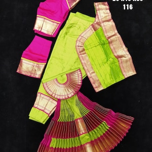 Puede incluir: Un traje de danza indio verde y rosa con falda, blusa y chal. La falda es plisada y tiene ribetes dorados. La blusa tiene un corpi&ntilde;o rosa y ribetes dorados. El chal es verde con ribetes dorados. El texto "BH SHP DVNY 26 K46 K36 116" est&aacute; impreso sobre un fondo blanco.