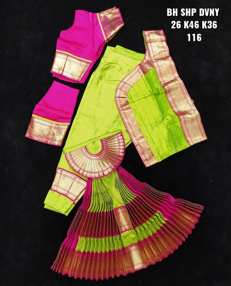 Puede incluir: Un traje de danza indio verde y rosa con falda, blusa y chal. La falda es plisada y tiene ribetes dorados. La blusa tiene un corpi&ntilde;o rosa y ribetes dorados. El chal es verde con ribetes dorados. El texto "BH SHP DVNY 26 K46 K36 116" est&aacute; impreso sobre un fondo blanco.