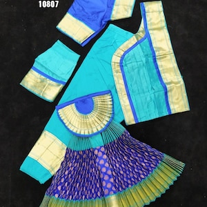 Puede incluir: Un traje de danza indio azul y verde con ribetes dorados. El traje incluye una falda, una blusa y una chalina. La falda est&aacute; plisada y tiene un patr&oacute;n azul y dorado. La blusa es azul y tiene ribetes dorados. La chalina es verde y tiene ribetes dorados. El traje est&aacute; etiquetado como "BH SUN SHP DVNY C19 28 K5 K5 10807".